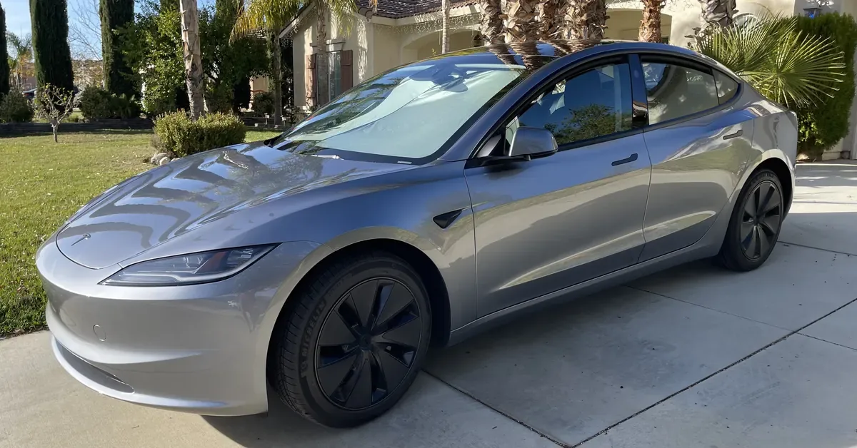 The site owner's grey Tesla Model 3 parked in a driveway